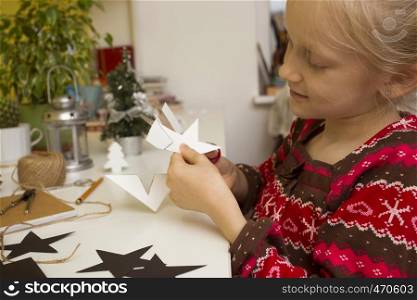 Christmas decorations. little girl made garlands stars