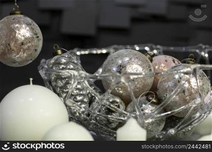 Christmas decorations of globular candles and vases with Christmas toys on a dark background with tiles. white candles decorated on a plate