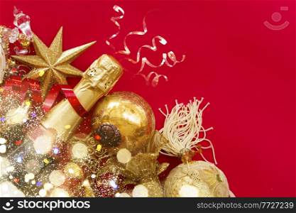 christmas decorations with bottle of champagne on red background flat lay scene with bokeh bright lights. new year decorations with bottle of champagne