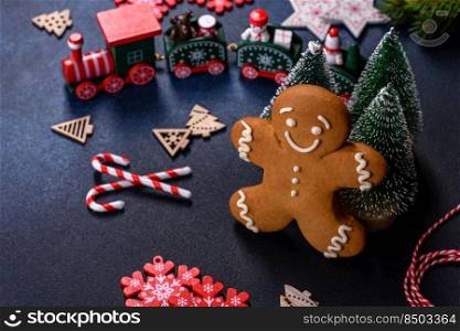 Christmas Decorations with Gingerbread man,fir tree branches and christmas background. Christmas homemade gingerbread cookies on a dark concrete table table