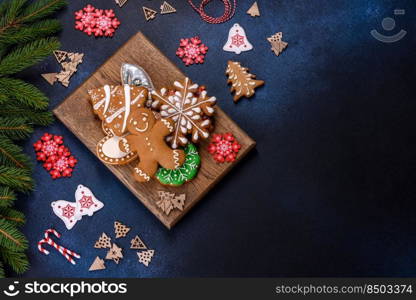 Christmas Decorations with Gingerbread man,fir tree branches and christmas background. Christmas homemade gingerbread cookies on a dark concrete table table