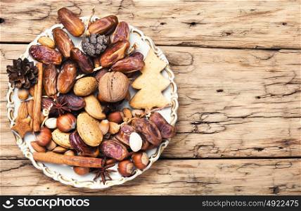 Christmas decorations with nuts, spices and bumps on a plate. Christmas plate with nuts, spices and cedar cone