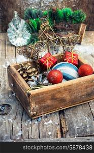 Christmas decorations. Wooden box full of Christmas toys and cones on wooden background.Selective focus