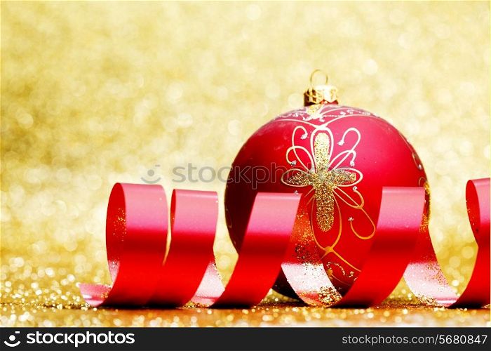 Christmas decorative ball and red ribbon on golden background