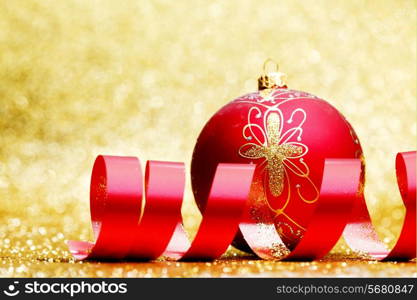 Christmas decorative ball and red ribbon on golden background