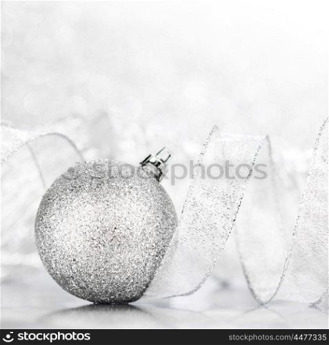 Christmas decorative ball and ribbon on silver glitter background