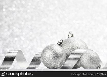 Christmas decorative balls and ribbons on light silver bokeh background