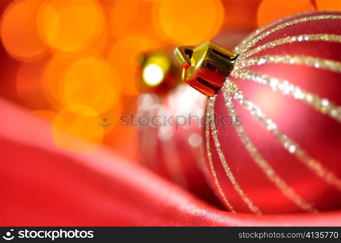 christmas decorative balls on red silk against blurred lights on background