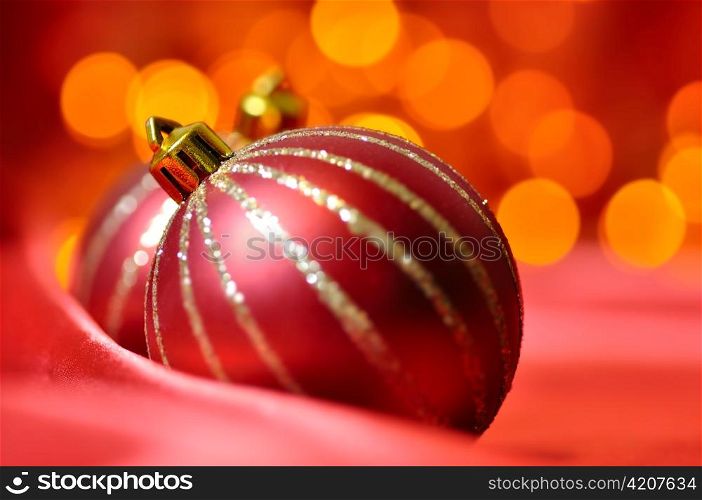 christmas decorative balls on red silk against blurred lights on background
