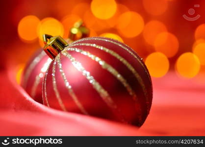 christmas decorative balls on red silk against blurred lights on background