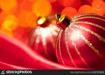 christmas decorative balls on red silk against blurred lights on background, shallow DoF