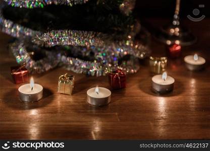 Christmas decorative tree is adorned with rain stands on the table with lit candles