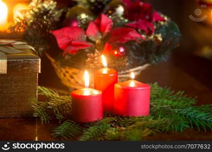 Christmas decorative wreath with burning red candles on table at living room