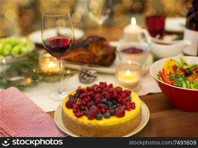 christmas dinner and eating concept - berry cake and other food on table at home. cake and other food on christmas table at home