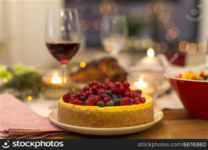 christmas dinner and eating concept - close up of berry cake and other food on table at home. cake and other food on christmas table at home