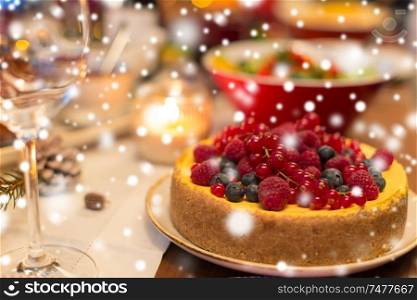 christmas dinner and eating concept - close up of berry cake and other food on table at home over snow. close up of cake and other food on christmas table