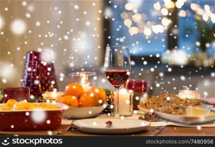 christmas dinner and eating concept - glass of red wine and food on table at home over snow. glass of red wine and food on christmas table