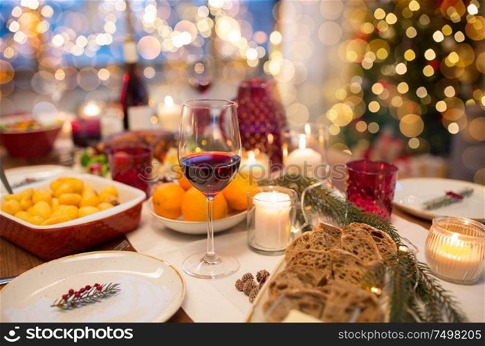 christmas dinner and eating concept - glass of red wine and food on table at home. glass of red wine and food on christmas table