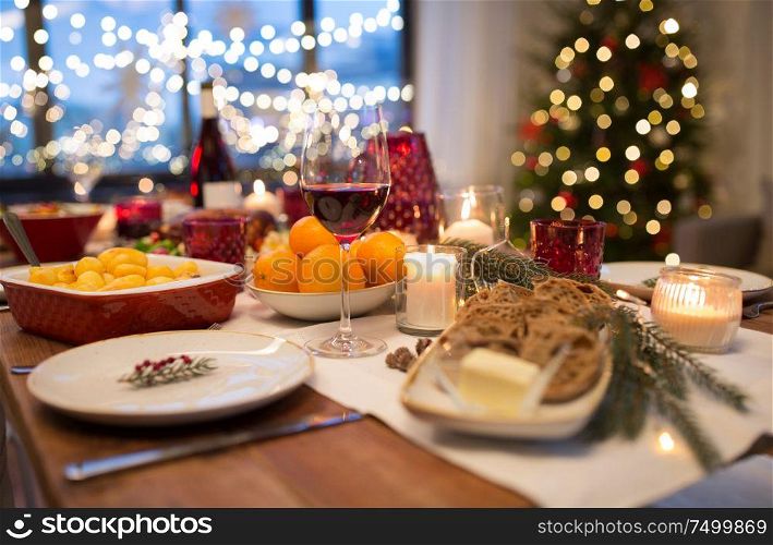 christmas dinner and eating concept - glass of red wine and food on table at home. glass of red wine and food on christmas table