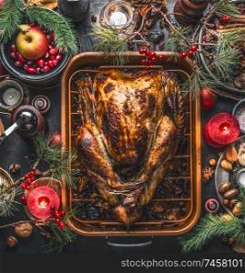 Christmas dinner. Roasted stuffed turkey served with fresh cranberries, pine branches on rustic background with burning candles, nuts, apple and little pumpkins, top view. Festive food flat lay