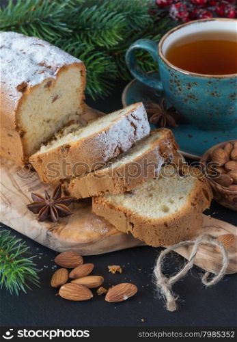 Christmas dinner with a cup of tea, sliced cake and spruce branches on a dark background