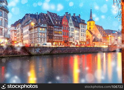 Christmas embankment in Strasbourg, Alsace. Picturesque Christmas quay and church of Saint Nicolas with mirror reflections in the river Ile during evening blue hour, Strasbourg, Alsace, France