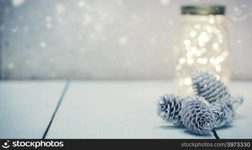 Christmas fairy lights in a mason jar glowing on rustic background.