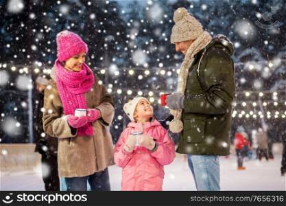 christmas, family and leisure concept - happy mother, father and daughter drinking hot tea at outdoor skating rink in winter over snow. happy family drinking hot tea on skating rink