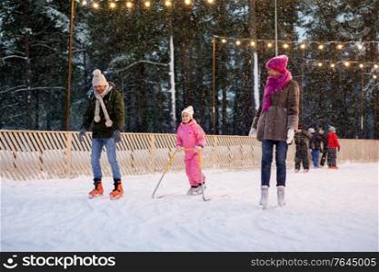 christmas, family and leisure concept - happy mother, father and daughter with support frame at outdoor skating rink in winter. happy family at outdoor skating rink in winter