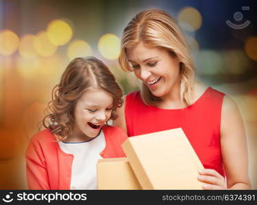 christmas, family and people concept - happy mother and daughter with gift box over festive lights background. happy mother and daughter with gift box