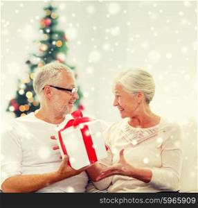 christmas ,family, holidays, age and people concept - happy senior couple with gift box and snow