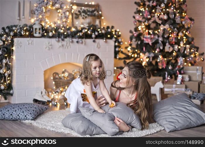 Christmas family photo shoot of mom and daughter.. My daughter and her mother lying on the pillows around the Christmas tr