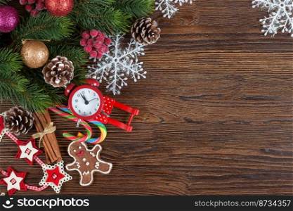 Christmas fir tree with decoration, gingerbread man and red clock on brown wooden background with copy space. Top view, flat lay. Christmas fir tree with decoration wooden background