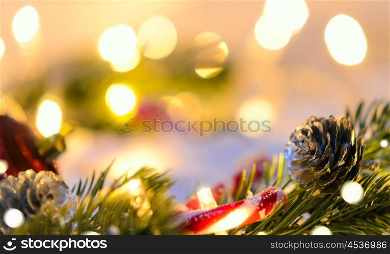 Christmas fir tree with lights and candy cane on snow in dark, view from above