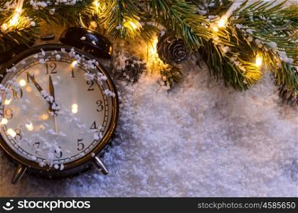 Christmas fir tree with lights and clock on snow in dark, view from above