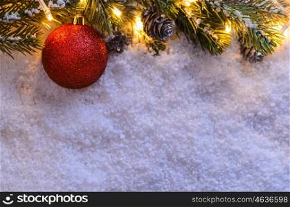 Christmas fir tree with lights and toy ball on snow in dark, view from above