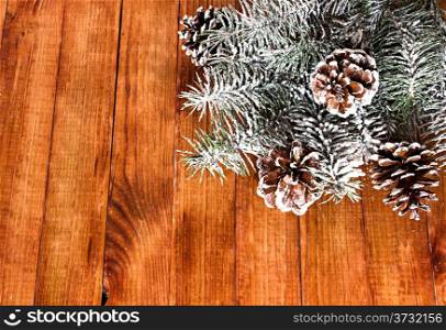 Christmas fir tree with snow, with cones on wooden background