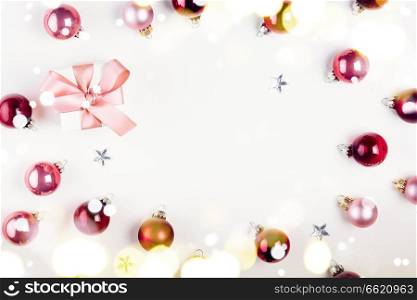 Christmas flat lay frame with pink abd violet glass balls and gift box with lights. Christmas flat lay scene with glass balls