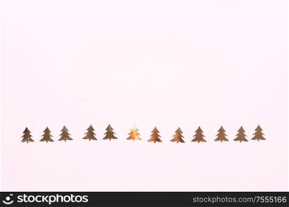 Christmas flat lay scene with golden fir tree confetti row, top view over pink. Christmas flat lay scene with golden decorations