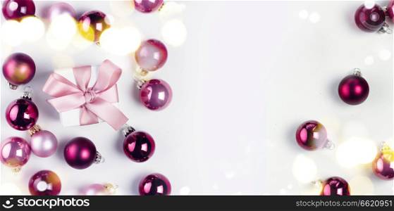 Christmas flat lay scene with pink abd violet glass balls and gift box with copy space on white. Christmas flat lay scene with glass balls