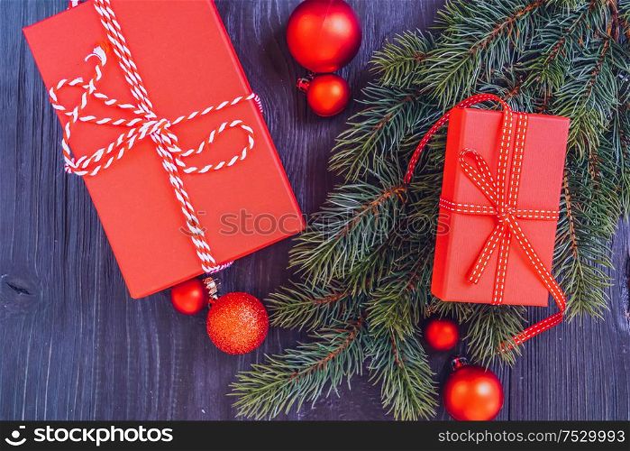 Christmas flat lay scene with red git box and green evergreen twigs, Christmas celebration and gift giving concept, copy space on wooden background. Christmas flat lay scene with golden decorations