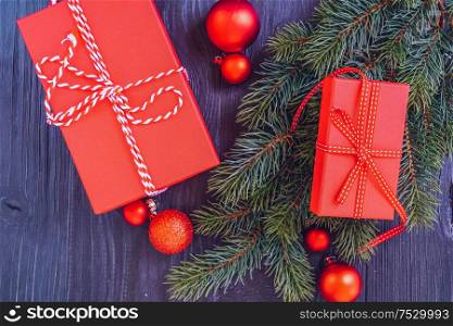 Christmas flat lay scene with red git box and green evergreen twigs, Christmas celebration and gift giving concept, copy space on wooden background. Christmas flat lay scene with golden decorations