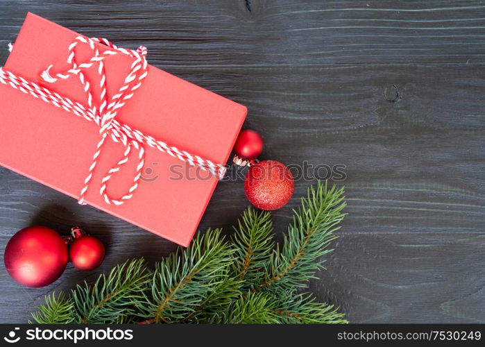 Christmas flat lay scene with red git box and green evergreen twigs, Christmas celebration and gift giving concept, copy space on wooden background. Christmas flat lay scene with golden decorations