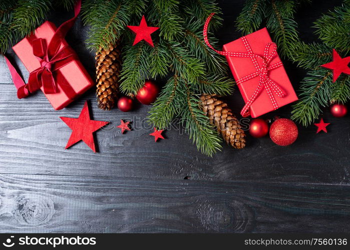 Christmas flat lay scene with red present boxes and green twigs, Christmas celebration and gift giving concept, wooden black background. Christmas flat lay scene with golden decorations