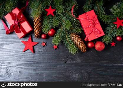 Christmas flat lay scene with red present boxes and green twigs, Christmas celebration and gift giving concept, wooden black background. Christmas flat lay scene with golden decorations