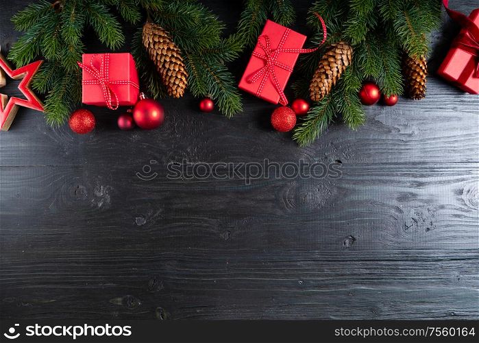 Christmas flat lay scene with red present boxes and green twigs, Christmas celebration and gift giving concept, copy space on wooden black background. Christmas flat lay scene with golden decorations