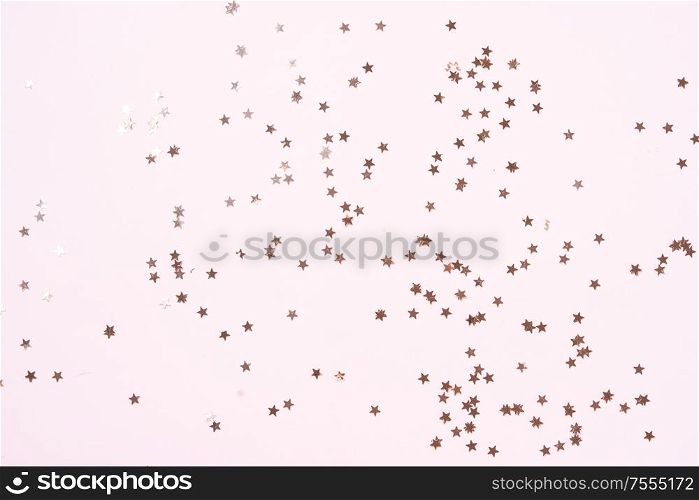 Christmas flat lay scene with scattered golden stars, top view over pink. Christmas flat lay scene with golden decorations