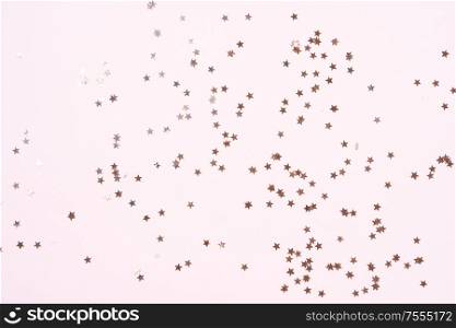 Christmas flat lay scene with scattered golden stars, top view over pink. Christmas flat lay scene with golden decorations