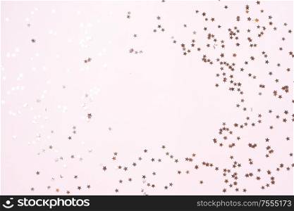 Christmas flat lay scene with scattered golden stars, top view over pink with copy space. Christmas flat lay scene with golden decorations