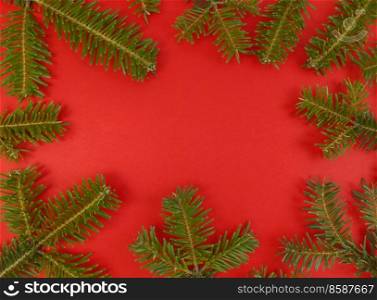 Christmas flat lay with fir tree branches frame on red background and copy space inside. Stock photo.. Christmas flat lay with fir tree branches frame on a red background and copy space inside. Stock photo.